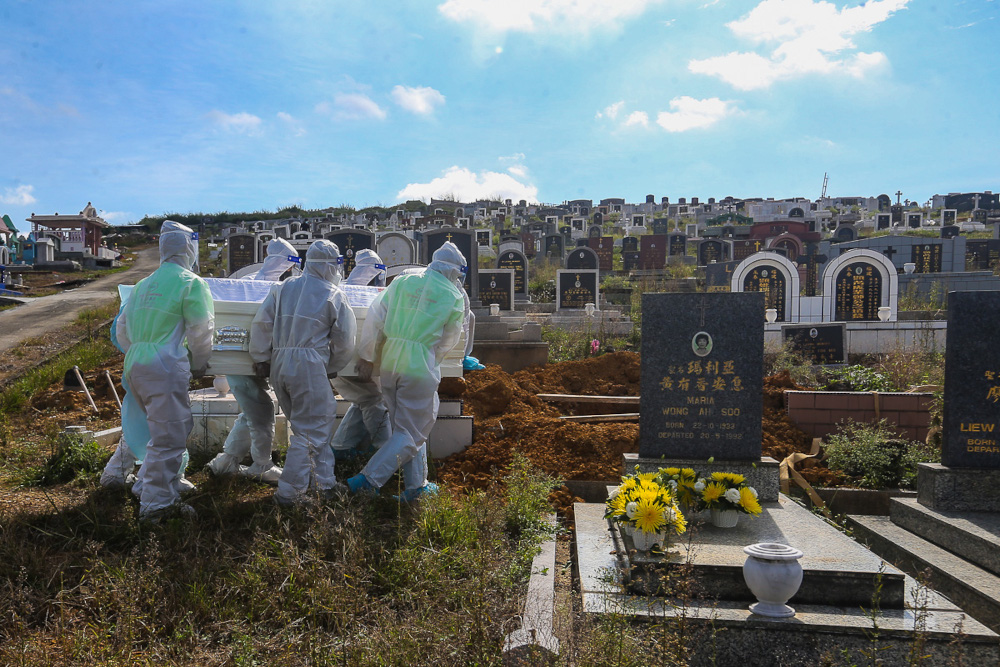 Workers wearing personal protective equipment (PPE) carry a coffin containing the body of a person who died from Covid-19 at the Meru Christian Cemetery in Klang, August 9, 2021. u00e2u20acu2022 Picture by Yusof Mat Isa