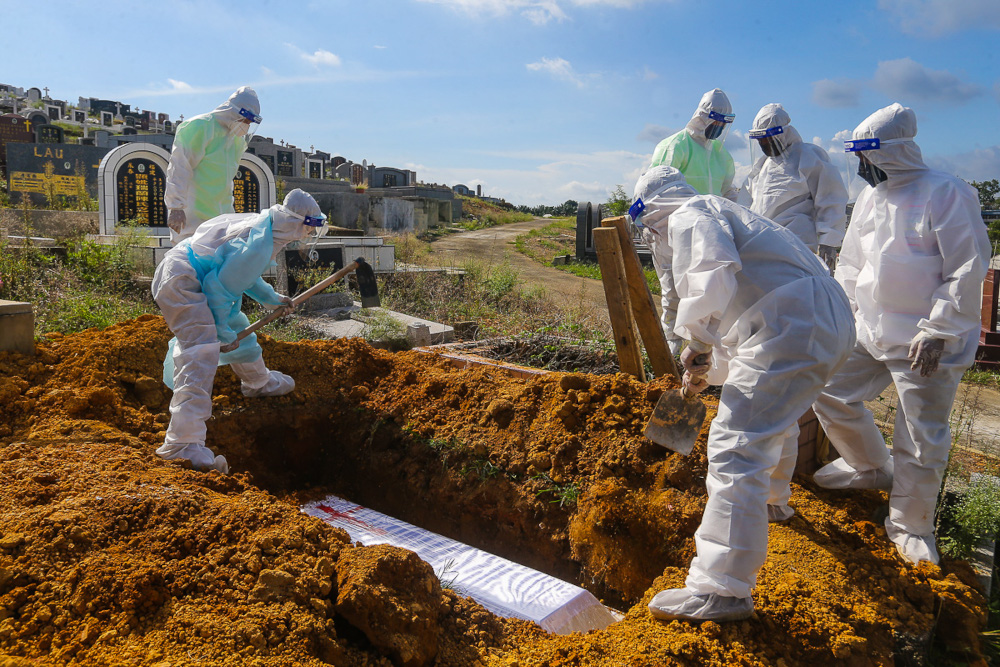 Workers wearing personal protective equipment (PPE) bury a person who died from Covid-19 at the Meru Christian Cemetery in Klang, August 9, 2021. u00e2u20acu2022 Picture by Yusof Mat Isa