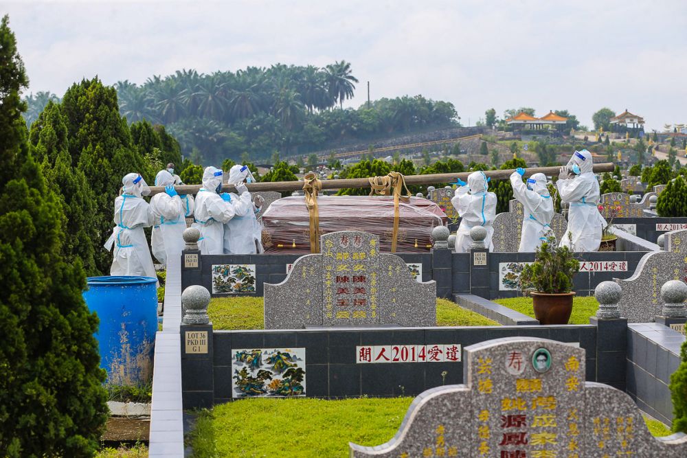 Workers wearing personal protective equipment carry a coffin containing the remains of a Covid-19 patient at a cemetery in Fairy Park, Klang August 1, 2021. u00e2u20acu201d Picture by Yusof Mat Isa