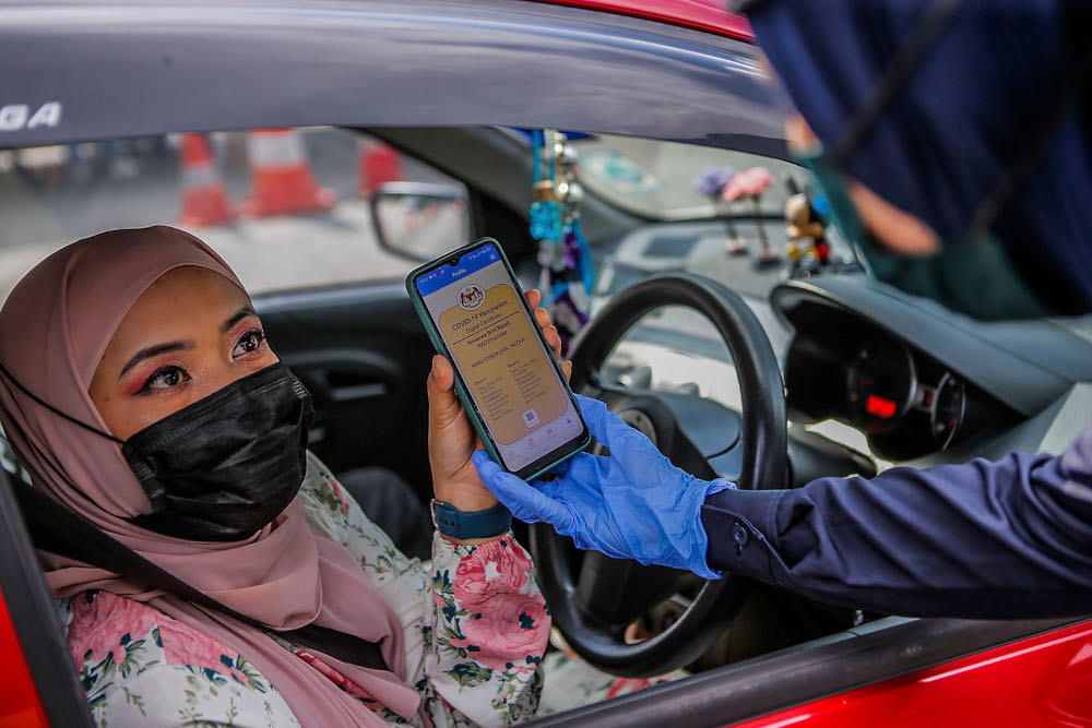 A woman shows the Covid-19 digital vaccination certificate to police at the Plaza Bentong roadblock, August 11, 2021. u00e2u20acu2022 Picture by Hari Anggara 