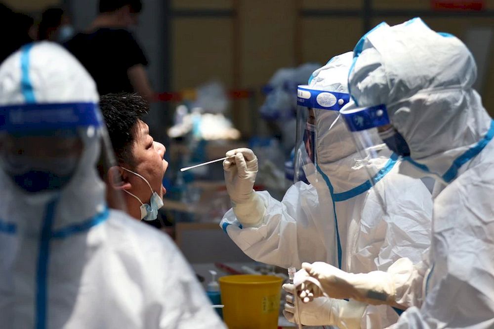 A medical worker in protective suit collects a swab from a resident for nucleic acid testing at a sports centre in Jiangning district, following new cases of Covid-19 in Nanjing, Jiangsu province, China July 21, 2021. u00e2u20acu201d cnsphoto via Reuters