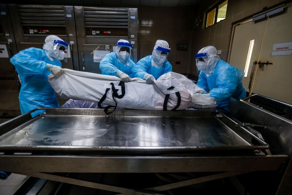 Forensics personnel transfer the body of a recently deceased Covid-19 patient out of the morgue at the Penang General Hospital, August 24, 2021. u00e2u20acu201d Picture by Sayuti Zainudin