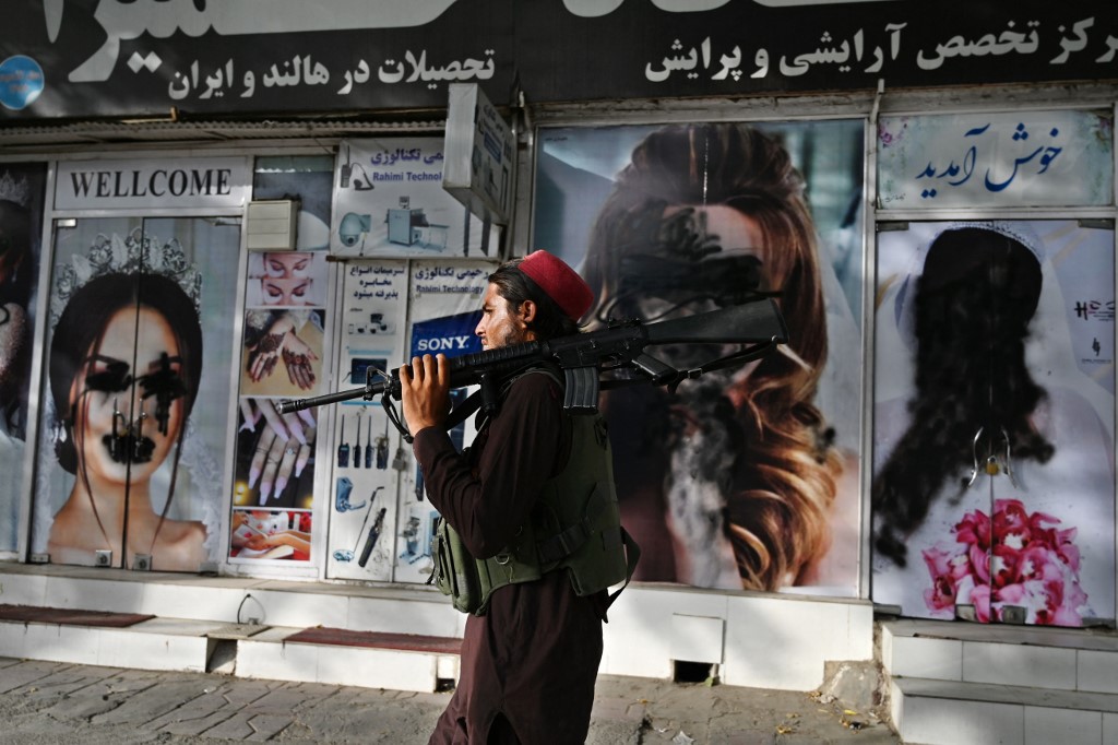 A Taliban fighter walks past a beauty salon with images of women defaced using spray paint in Shar-e-Naw in Kabul on August 18, 2021. u00e2u20acu201d AFP pic