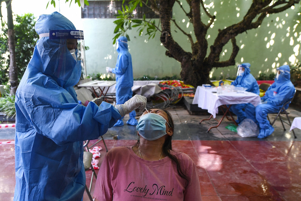A health worker wearing personal protective equipment (PPE) collects a swab sample from a woman for Covid-19 coronavirus testing in Hanoi August 29, 2021. u00e2u20acu201d AFP pic