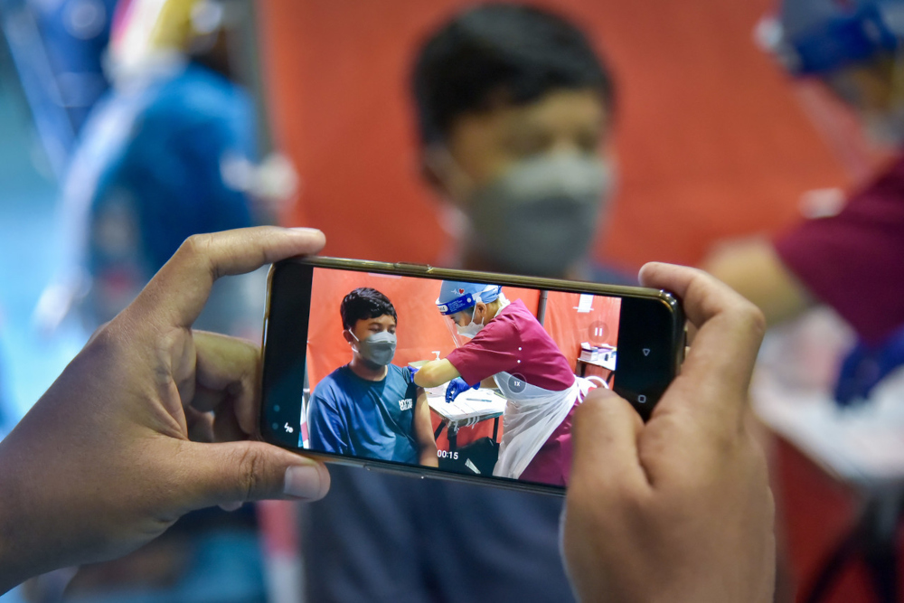 A father records his son receiving the Covid-19 vaccination at the Labuan Matriculation College vaccination centre, September 24, 2021. u00e2u20acu201d Bernama pic