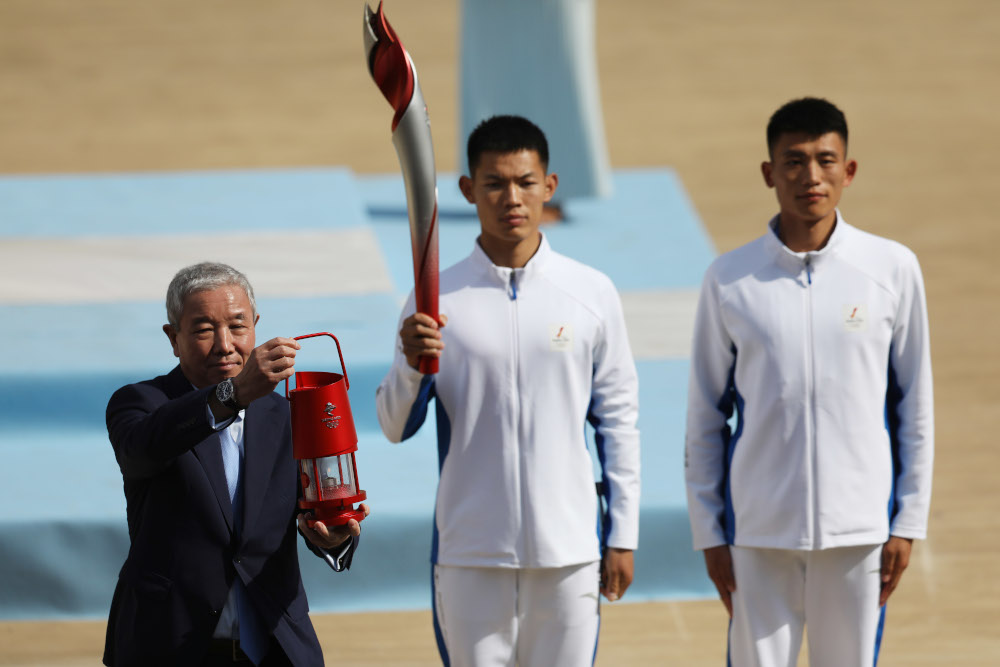 北京冬奥组委副主席于再清（左）在希腊圣火采集仪式后接获火种并将其带回中国。-路透社-