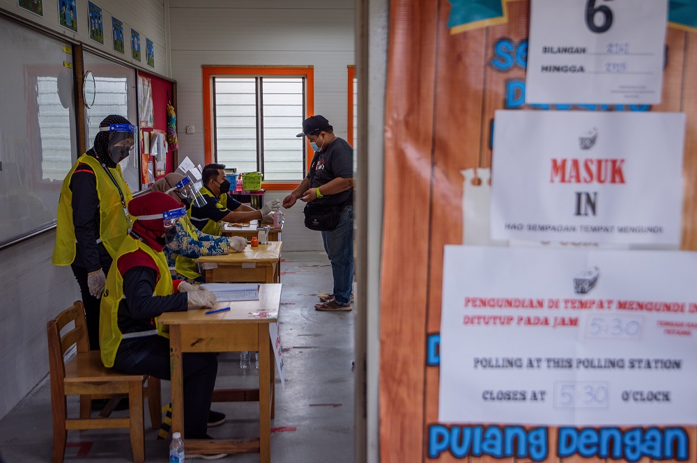 An election commission officer marks a voteru00e2u20acu2122s finger with indelible ink at the SK Durian Tunggal polling station in Durian Tunggal during the Melaka state election November 20, 2021. u00e2u20acu2022 Picture by Shafwan Zaidon