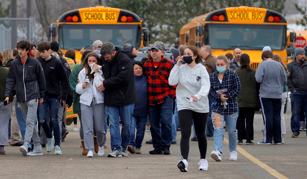 Parents walk away with their kids from the Meijeru00e2u20acu2122s parking lot where many students gathered following an active shooter situation at Oxford High School in Oxford, Michigan November 30, 2021. u00e2u20acu201d Picture by Eric Seals-USA TODAY Network via Reuters