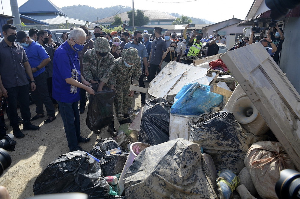 Prime Minister Datuk Seri Ismail Sabri Yaakob lends a hand to an Malaysian Air Force personnel in cleaning up the flood-affected areas in Taman Nanding in Hulu Langat December 26, 2021. u00e2u20acu201d Bernama pic