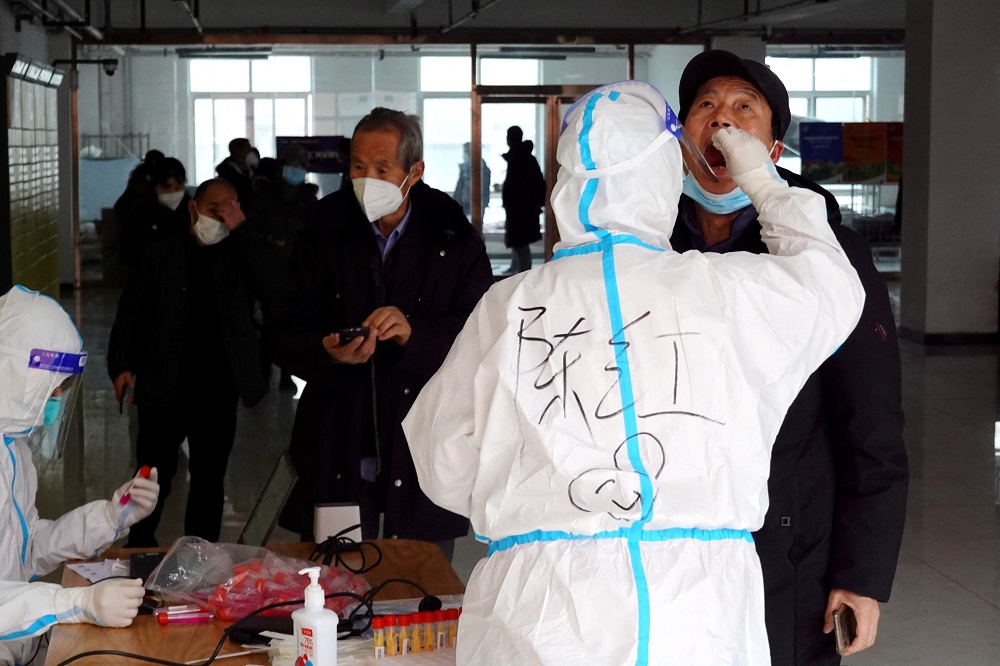 A medical worker in protective suit collects a swab sample from a man in Xian, Shaanxi province, China December 27, 2021. u00e2u20acu2022 cnsphoto via Reuters