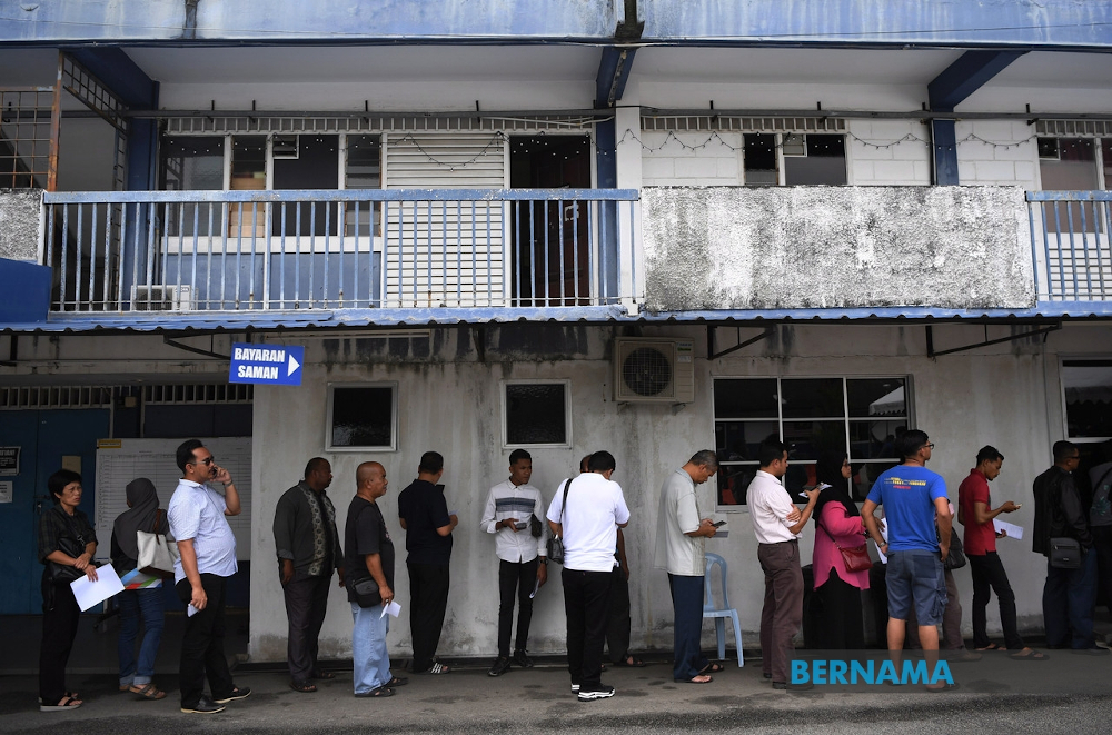 People wait their turn to pay outstanding traffic summonses at a police station. u00e2u20acu201d Picture via Twitter/Bernama