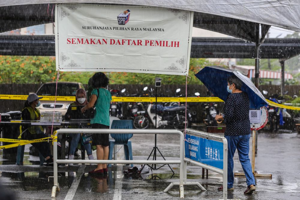 大雨无阻砂拉越人履行公民责任，选民撑伞抵达古晋中华小学的投票中心。-Yusof Mat Isa摄-