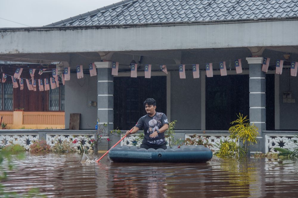 A man rides an inflatable raft amid flooding in Kampung Jalan Kebung, Shah Alam December 18, 2021. u00e2u20acu2022 Picture by Shafwan Zaidonnnn