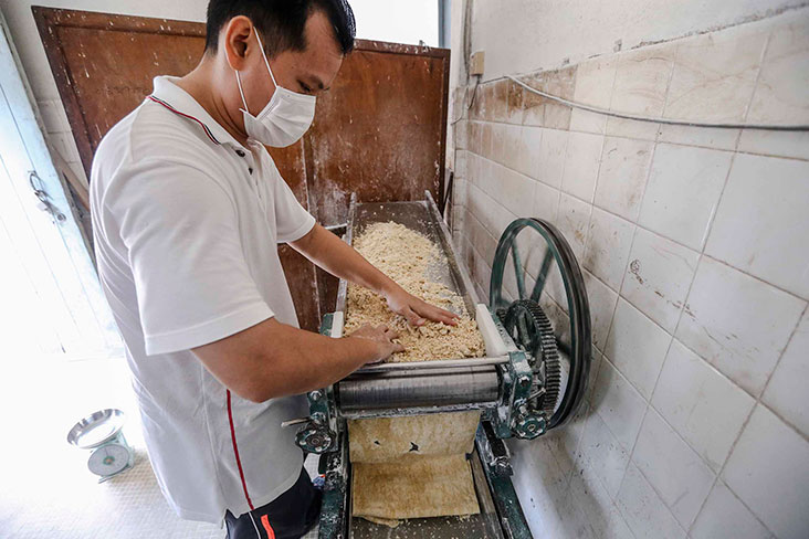 老板把面粉团压成面皮。-Firdaus Latif摄-