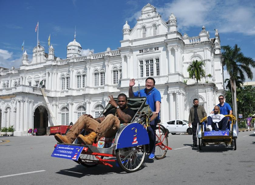 Low (centre) pedals a trishaw carrying US rapper Busta Rhymes in George Town on April 19, 2013. u00e2u20acu201d Picture by KE Ooi