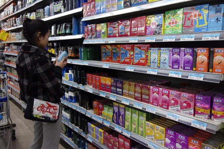 A woman browses items for sale beside a shelf of condoms at a supermarket in Beijing on April 24, 2013. u00e2u20acu201d AFP pic