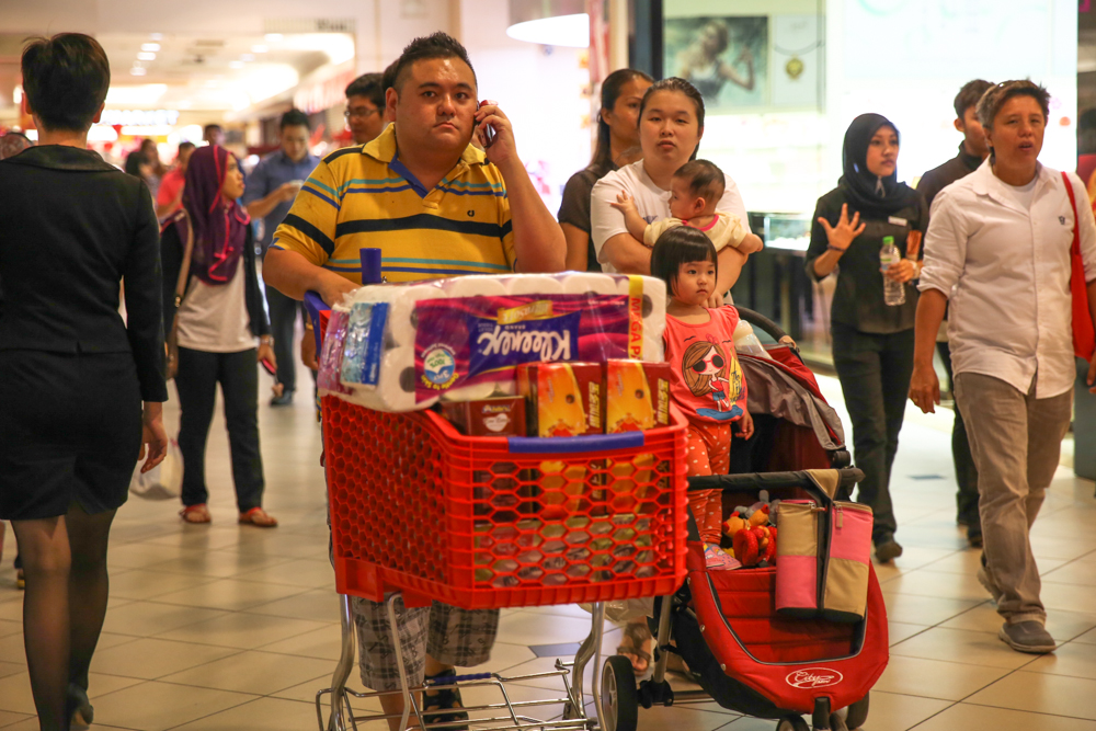 A family push a cart to their car after buying groceries at a hypermarket in a shopping mall in Kuala Lumpur. u00e2u20acu201d Picture by Saw Siow Fengn