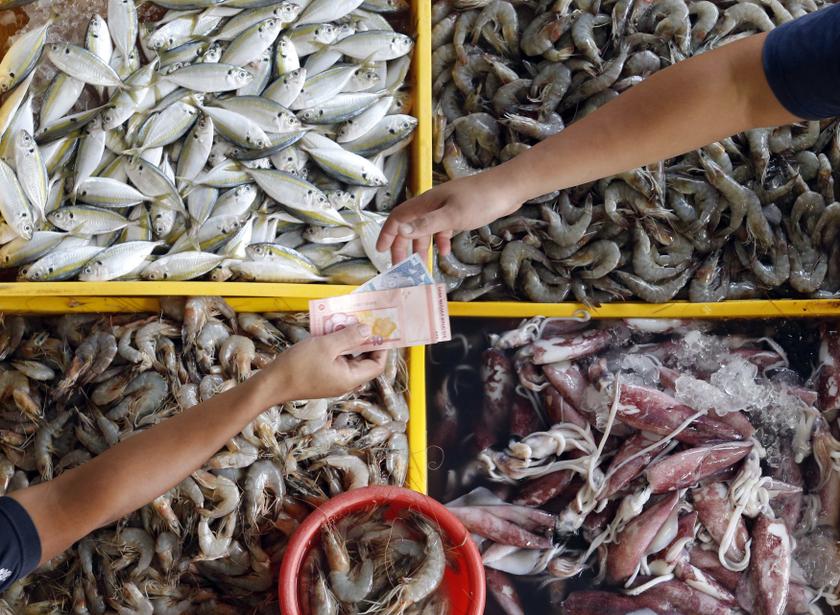 A seafood stall keeper returns change to a customer at a market in Kuala Lumpur August 27, 2013. u00e2u20acu201d Reuters pic