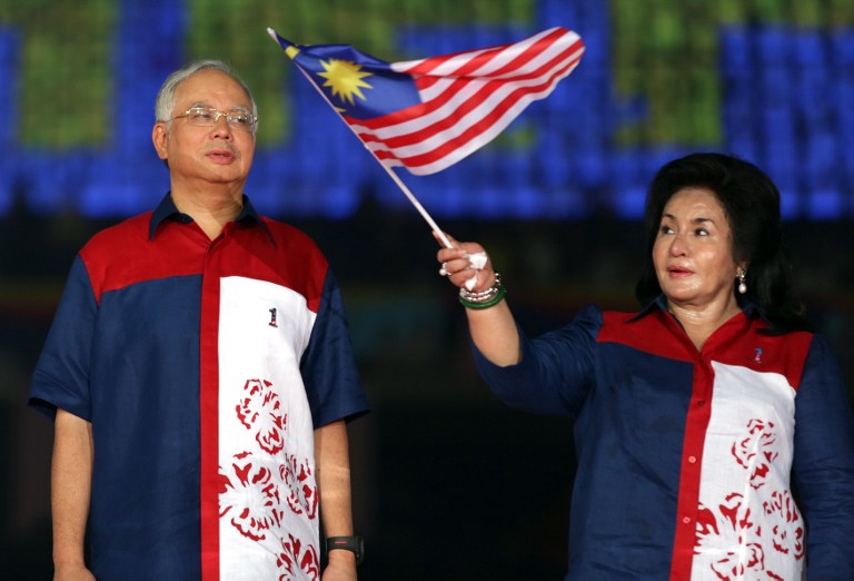 Prime Minister Datuk Seri Najib Razak (left) looks on as Rosmah  waves a national flag during a rally to celebrate country's 55th Independence Day in Bukit Jalil Stadium. u00e2u20acu201c AFP pic