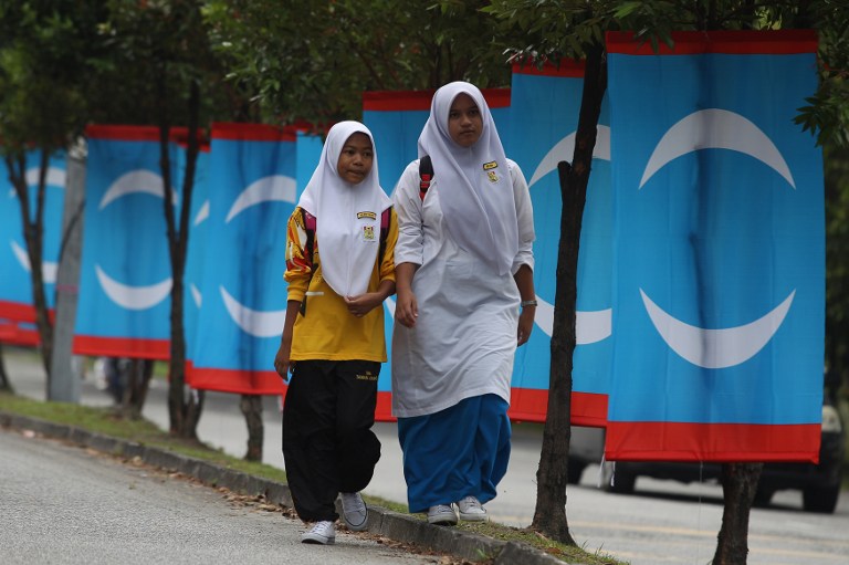 School children walk past Malaysia opposition PKR flags ahead of the 13th upcoming general elections in Kuala Lumpur on April 8, 2013. u00e2u20acu201c AFP pic
