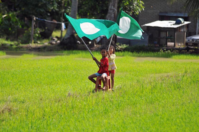 Children playing with the PAS flag in a paddy field near their home in Sungai Limau. u00e2u20acu201d Picture by K.E. Ooi