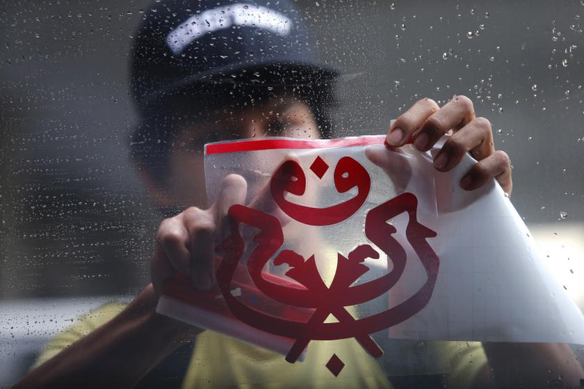 A worker applies a sticker of the United Malays National Organisation logo onto a van's window during preparations ahead of the UMNO annual assembly in Kuala Lumpur November 28, 2013. The UMNO assembly will take place from December 3-7.u00c2u00a0u00e2u20acu201d Reuters pic